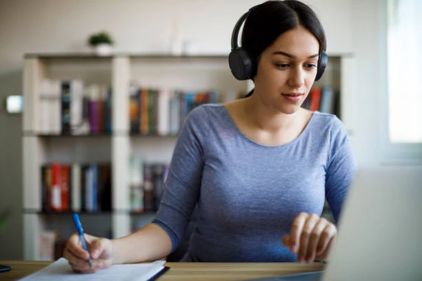 Mujer tomando nota mientras mira una clase online